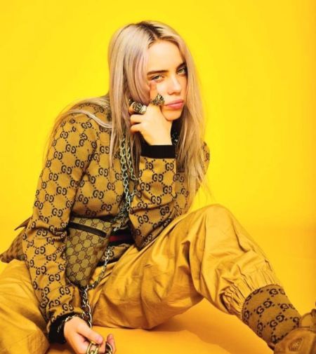 billie in all yello gucci outfit in a yellow back drop 